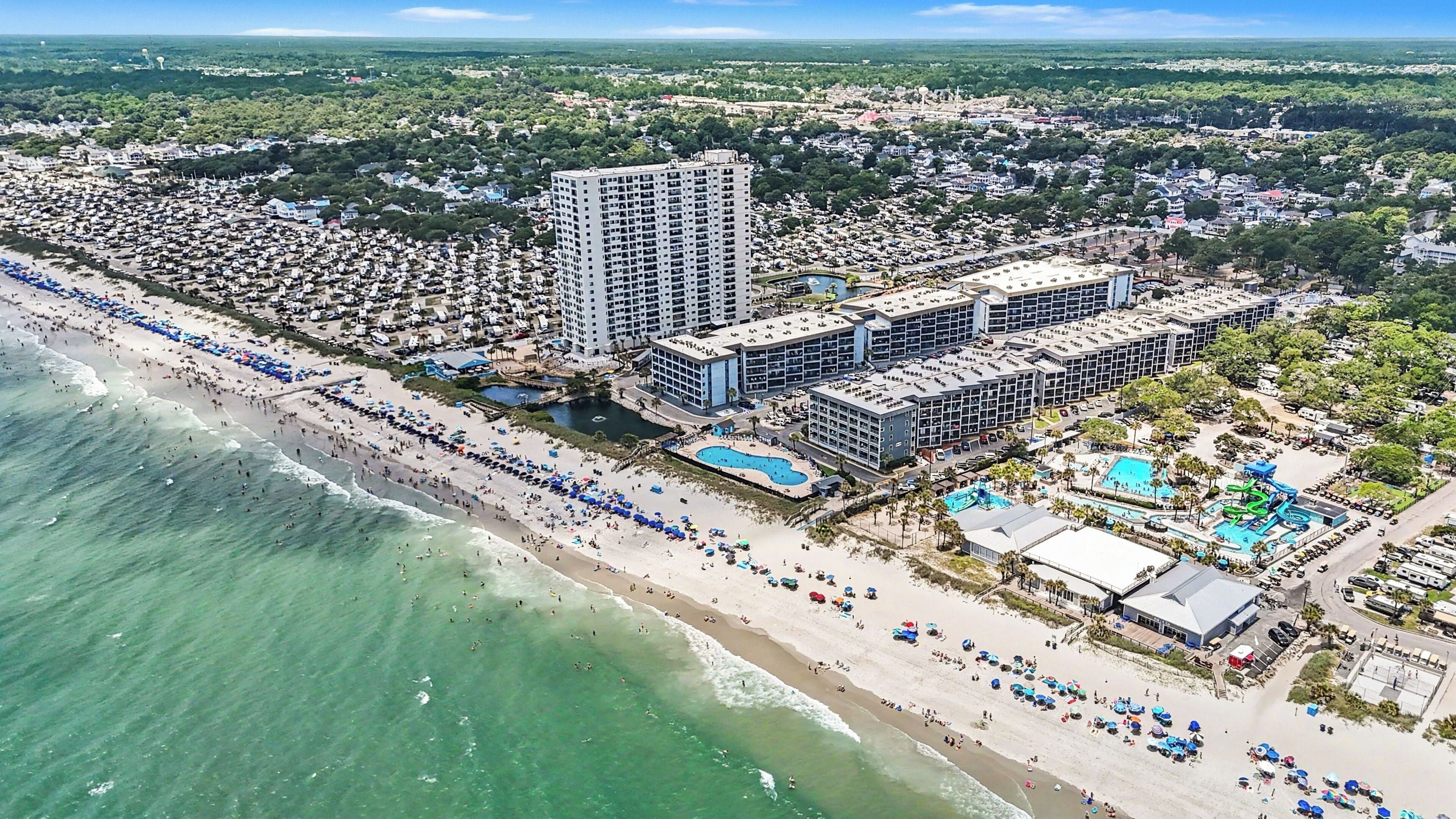 Un complex turístic costaner amb diversos edificis hotelers, una platja i un parc aquàtic.