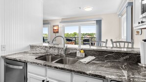 A kitchen with a granite countertop, double sink, and a view of the outdoors.