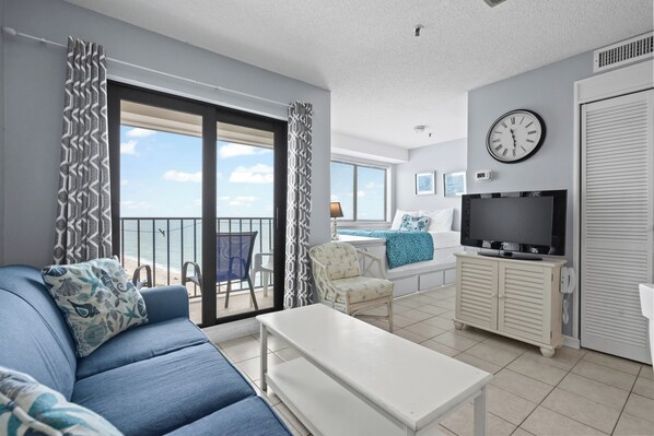 A modern living room with a sofa, a TV, and a balcony with a view. - T1807 at the Myrtle Beach Resort (Myrtle Beach)