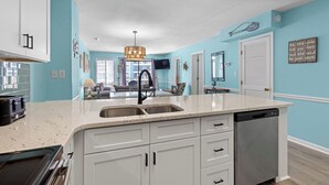 Una cocina moderna con armarios blancos, una isla grande con un fregadero y un lavavajillas.