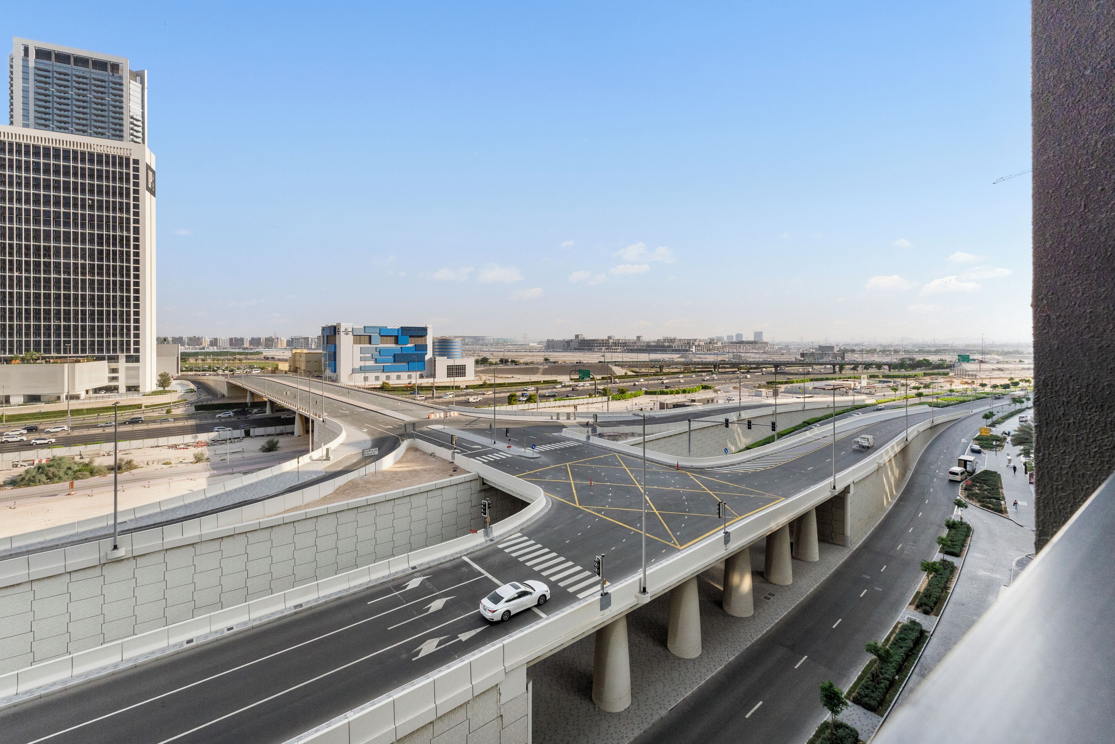 Eine mehrspurige Autobahnkreuzung mit moderner Architektur, darunter ein markantes, blaues Gebäude.