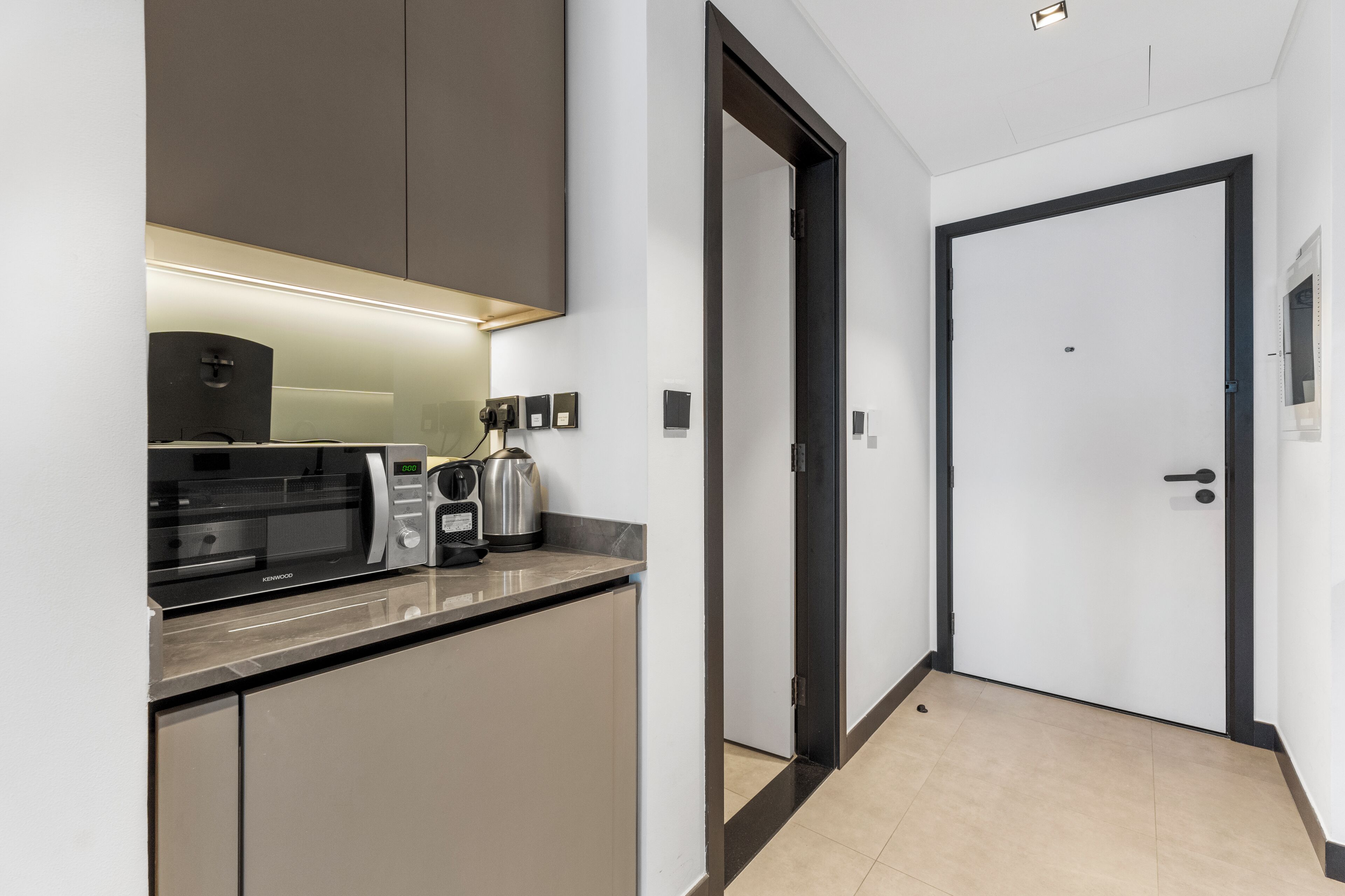 A modern kitchen with a built-in microwave, kettle, and coffee maker.