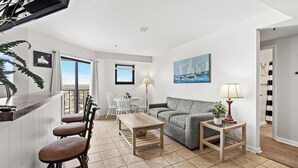 A modern living room with a sofa, a coffee table, and a TV. There is a balcony with a view of the sea. - T1210 Myrtle Beach Resort (Myrtle Beach)