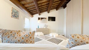 Een slaapkamer met een bed, gestreepte kussens, een dressoir, een televisie en een decoratie met een nautisch thema.