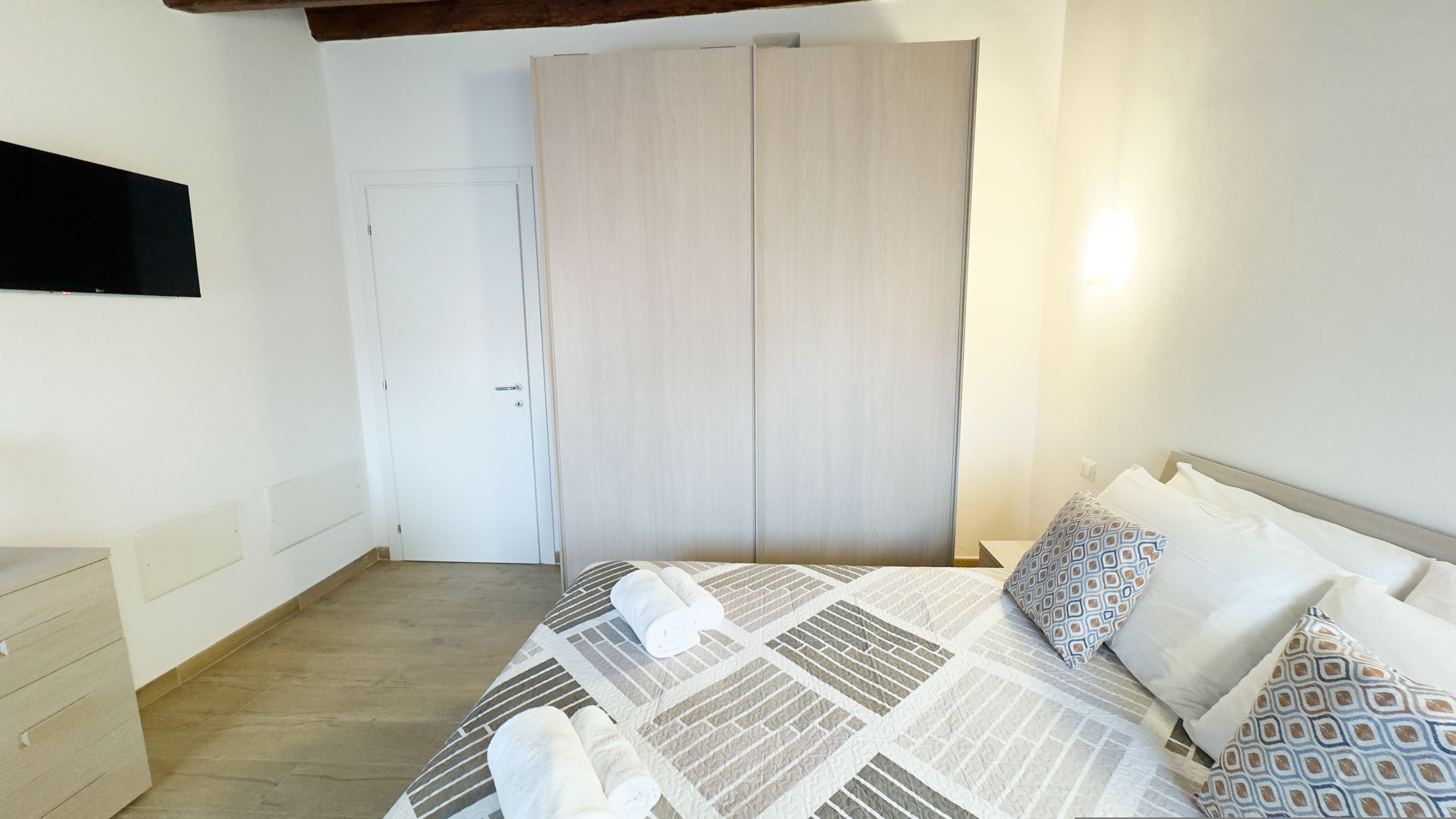A bedroom with a bed, a wardrobe, a dresser, and a door.
