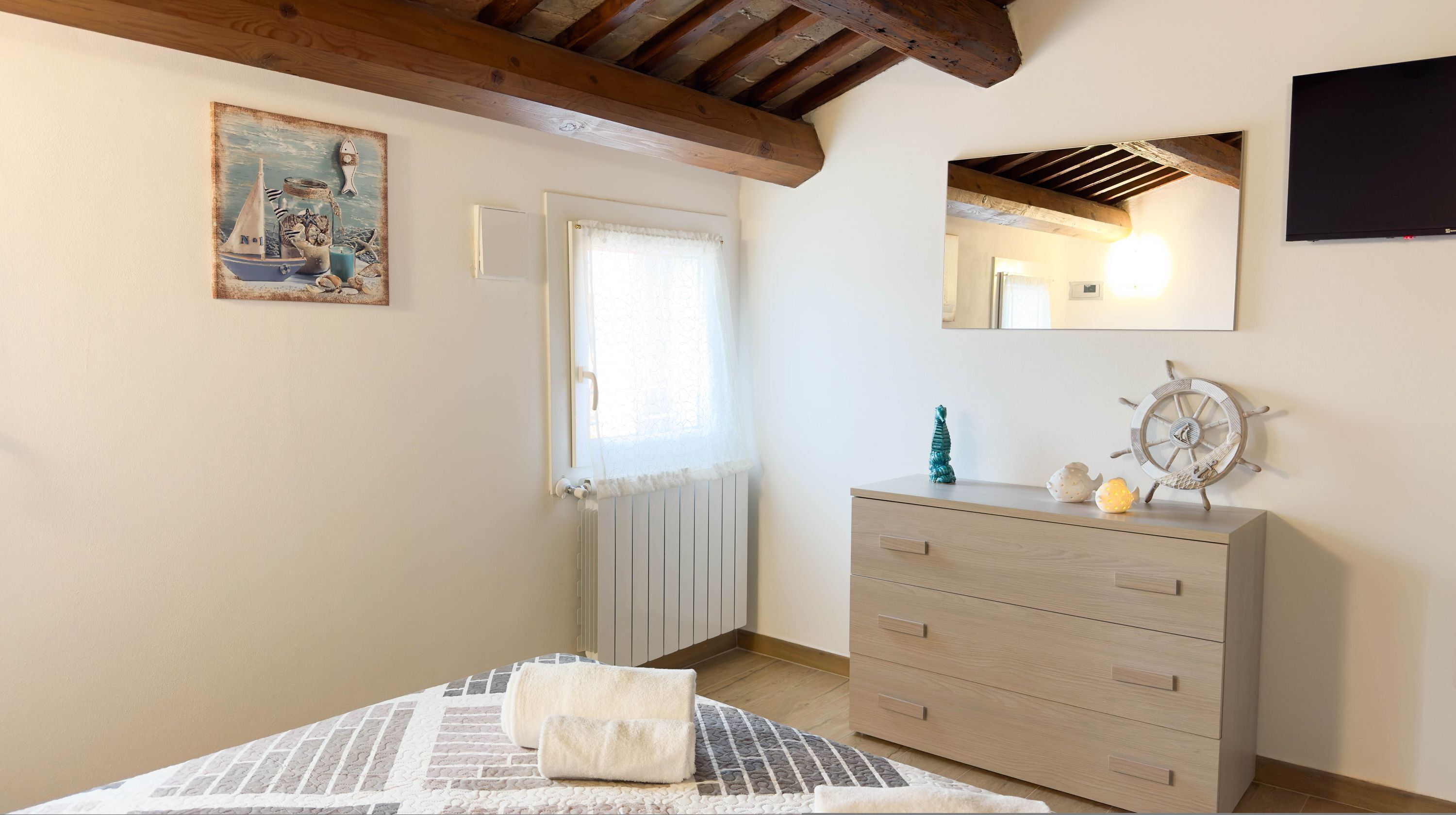 Ein Schlafzimmer mit einem Bett, einem Schminktisch, einem Gemälde, einem Spiegel und einem Fenster.