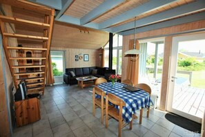 A cozy living room with a wooden staircase, a sofa, and a dining area with a checkered tablecloth. - Exklusives Skandinavisches Ferienhaus (Rechlin)