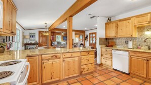A spacious kitchen with wooden cabinets, a granite countertop, and a dishwasher. - Lawlis Lodge I Families, Star Gazing (Wimberley)