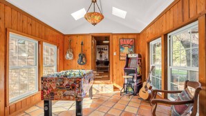 A room with wooden walls, a foosball table, guitars, and a 'Bang!' arcade machine. - Lawlis Lodge I Families, Star Gazing (Wimberley)