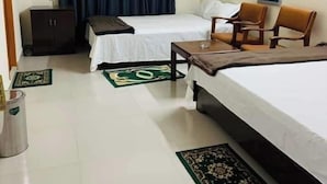 Ein Hotelzimmer mit zwei Betten, einem Schreibtisch, einem Stuhl, einem Schrank und einem Deckenventilator.