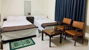 Ein Hotelzimmer mit zwei Betten, einem Schreibtisch, einem Stuhl, einem Spiegel und einem Fenster mit Vorhängen.