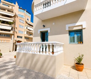A modern apartment building with balconies, potted plants, and a clear sky.
