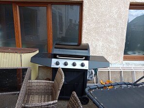A patio with a grill, wicker chairs, and a trampoline. - Les randonneurs Room (Aydat)