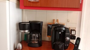 A kitchen with a refrigerator, coffee maker, toaster, and a mobile phone on the counter. - Les randonneurs room  (Aydat)