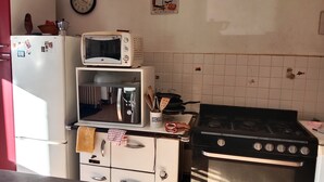A kitchen with a white refrigerator, a microwave, a stove, and a clock on the wall. - Les randonneurs room  (Aydat)