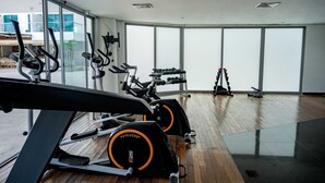 Una palestra con macchinari cardio, panche per pesi e manubri.