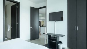 Una camera d'albergo moderna con un letto grande, una TV a parete, una scrivania e un armadio.