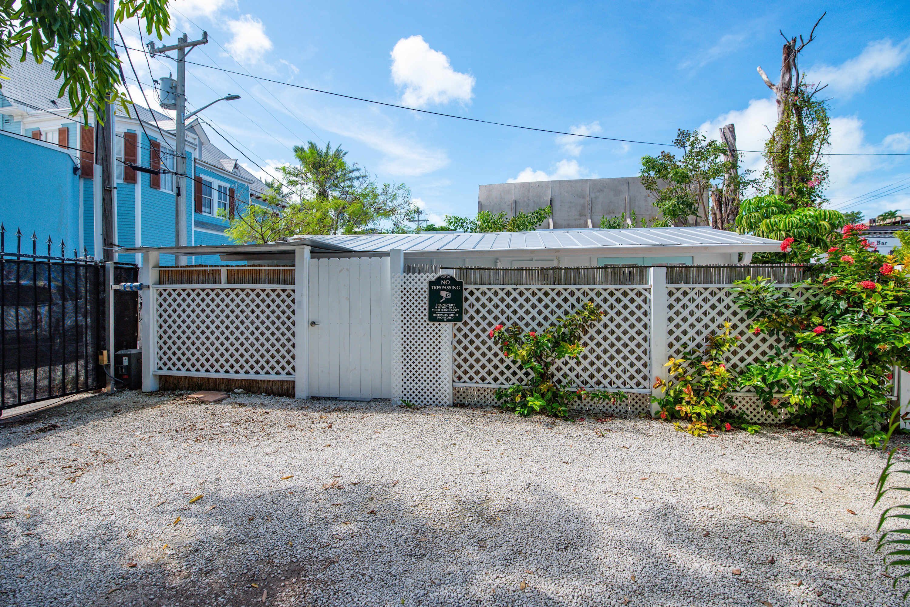 A gated area with a white fence, a small shed, and a gravel driveway.