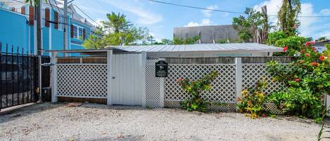 A gated area with a white fence, a small shed, and a gravel driveway.