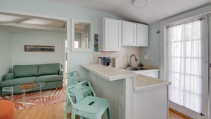A compact living space with a kitchenette, a sofa, a dining area with chairs, and a large window. - New The Cottage at James House (Key West)
