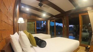 A bedroom with a large bed, wooden walls, and a view of the outside.