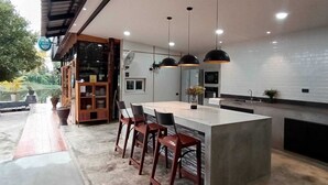 A modern kitchen with a central island, pendant lighting, and a view of the outdoors.