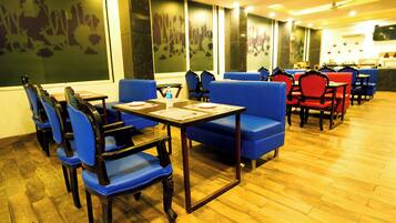 Un restaurante con asientos tapizados en azul y mesas de madera, con piso de madera y un amplio ventanal con vistas a la ciudad.
