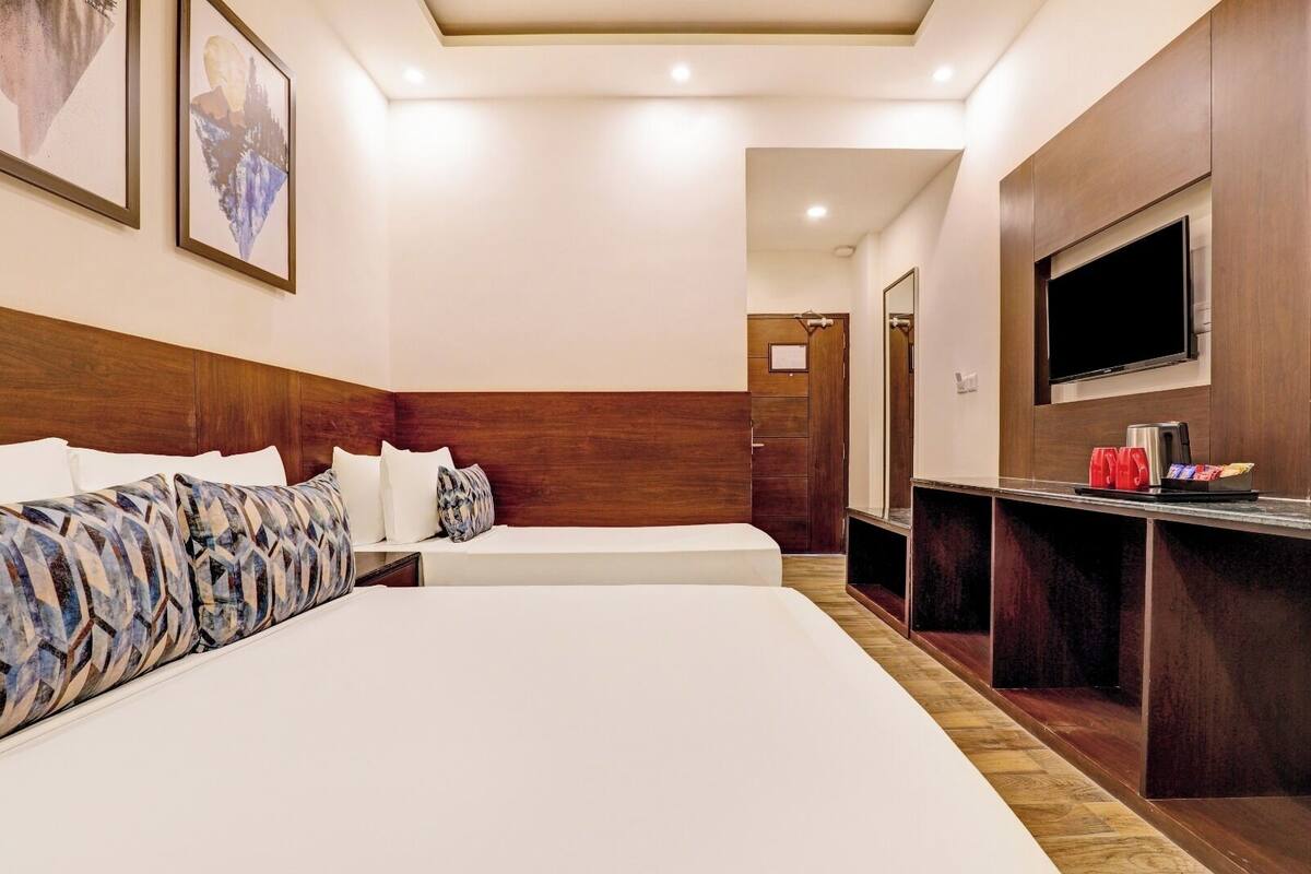 A hotel room with two beds, a TV, a minibar, and a wooden headboard.