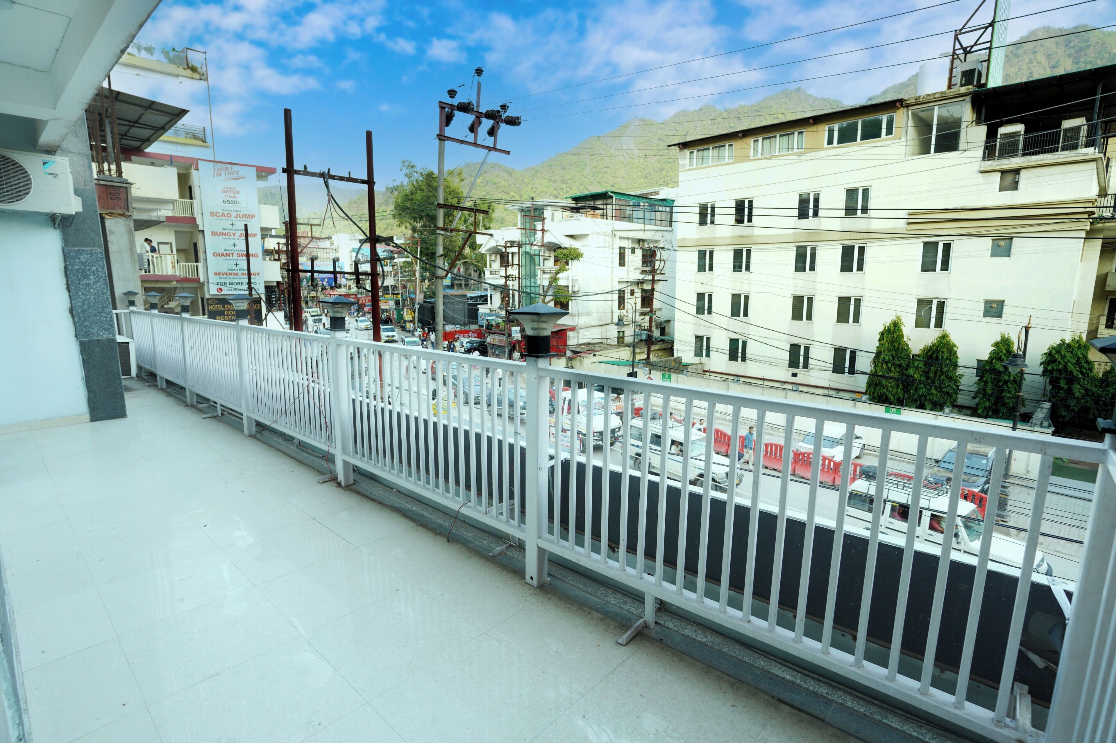 A balcony with a white railing overlooking a busy street with buildings and a mountain in the background.