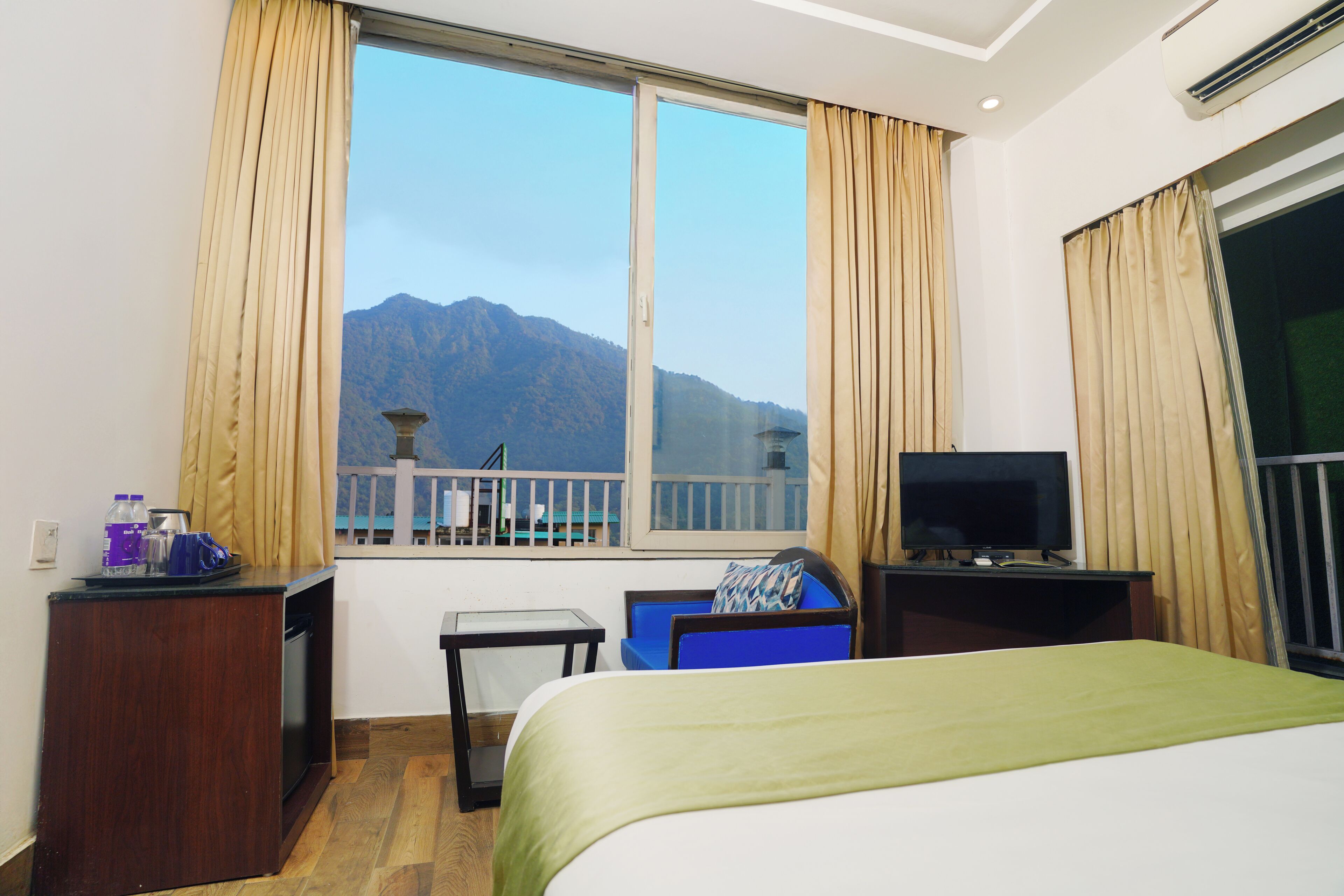 Habitación de hotel con cama, televisión, escritorio y ventana con vista a la montaña.