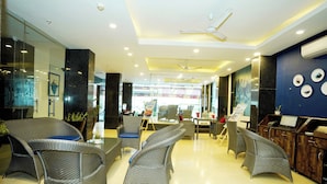 A modern hotel lobby with wicker furniture, a reception desk, and a ceiling fan. - N3N Ganga Retreat by Stotrak (Rishikesh)