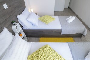 A modern hotel room with two beds, a small table, a lamp, and a yellow rug. - Two-bedroom apartment with Terrace and Pool (Novalja)
