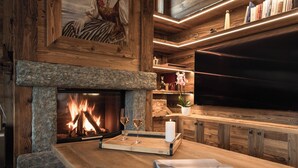 Una sala de estar acogedora con chimenea de piedra, estanterías de madera, televisor de pantalla plana y una mesa de centro de madera.