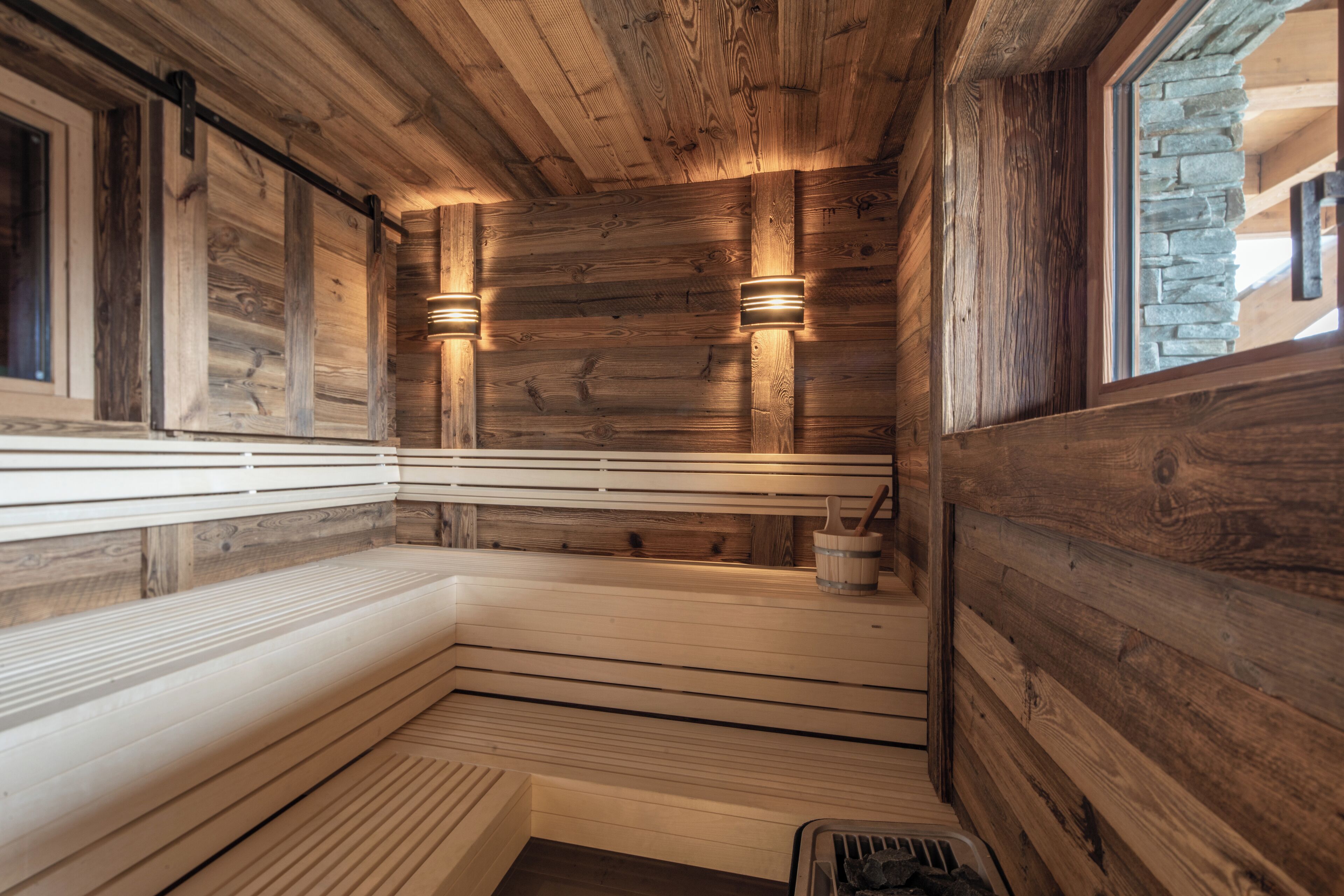 Uma sauna de madeira com bancos e paredes de pedra.