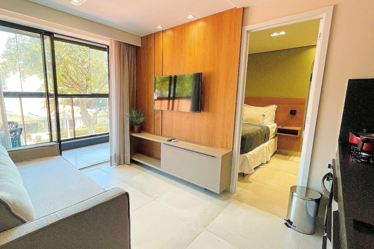 Une chambre d’hôtel moderne équipée d’un canapé, d’un téléviseur fixé au mur, d’un lit et d’une petite table.