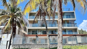 A multi-story hotel with balconies, a stone facade, and palm trees. - Hyde Park - By Living (João Pessoa)