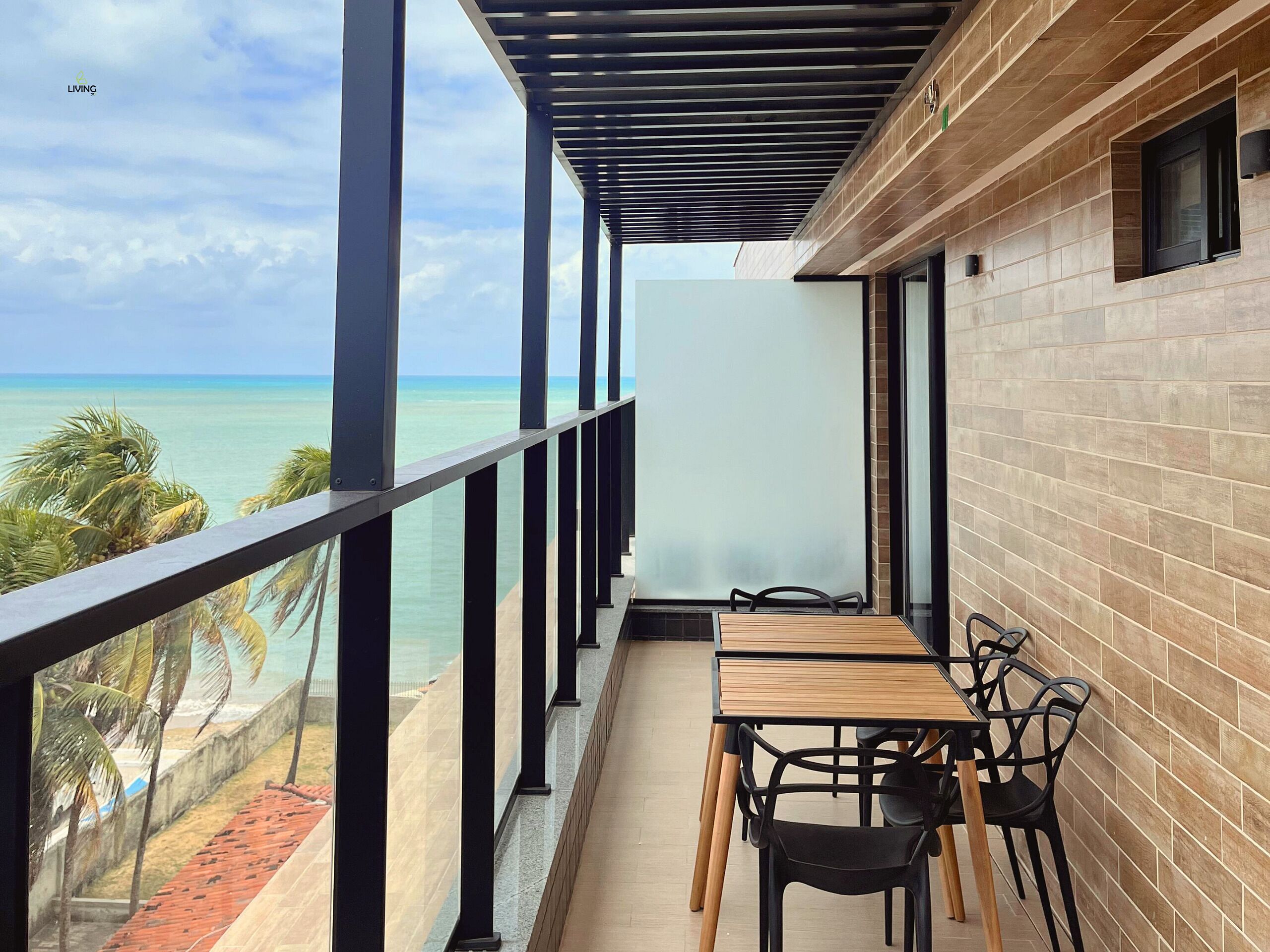 A balcony with a view of the ocean, a table with chairs, and a brick wall.