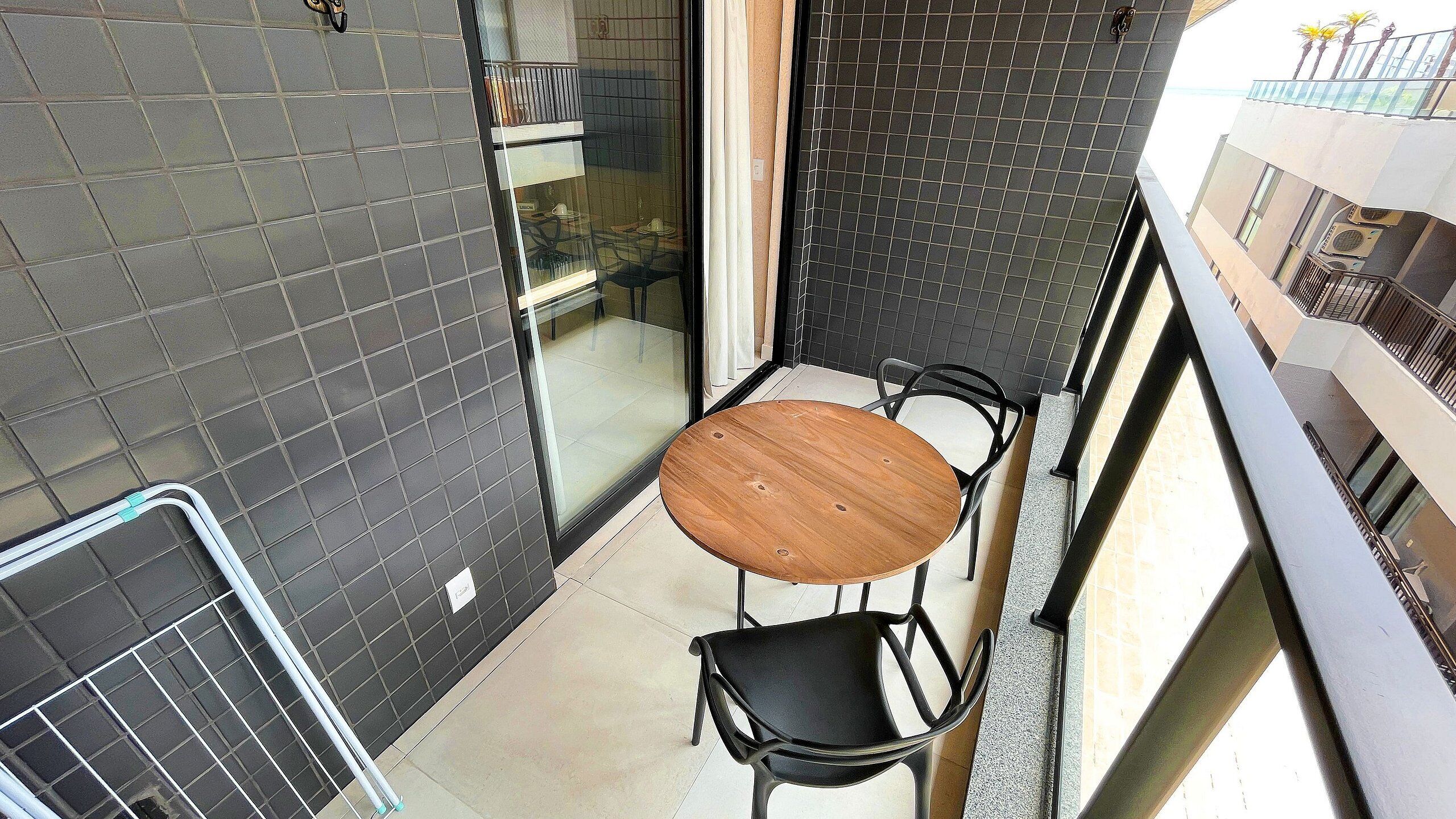 A small balcony with a round wooden table and two black chairs.
