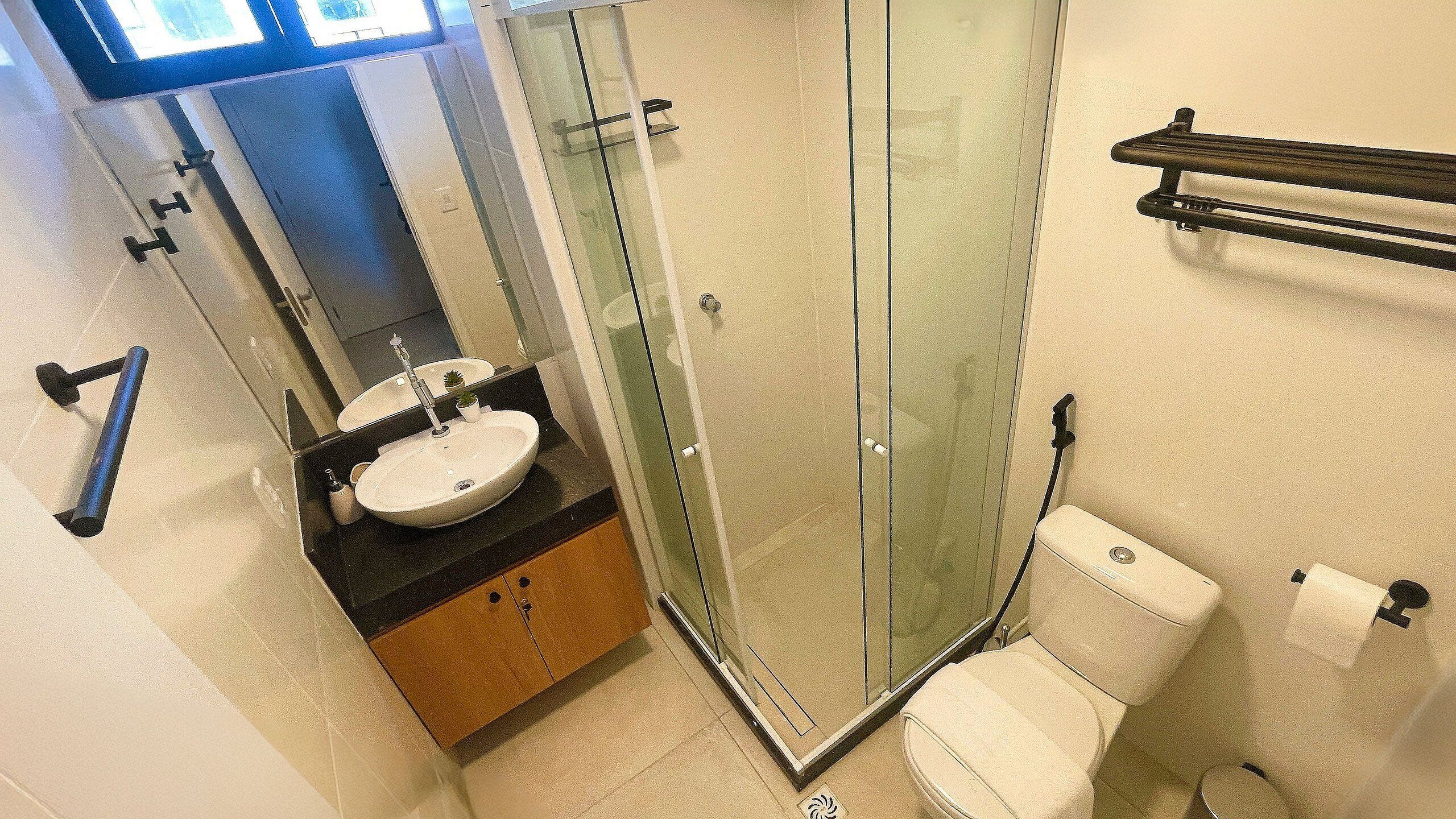A bathroom with a glass shower enclosure, a sink with a mirror, and a toilet.