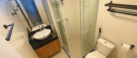 A bathroom with a glass shower enclosure, a sink with a mirror, and a toilet.