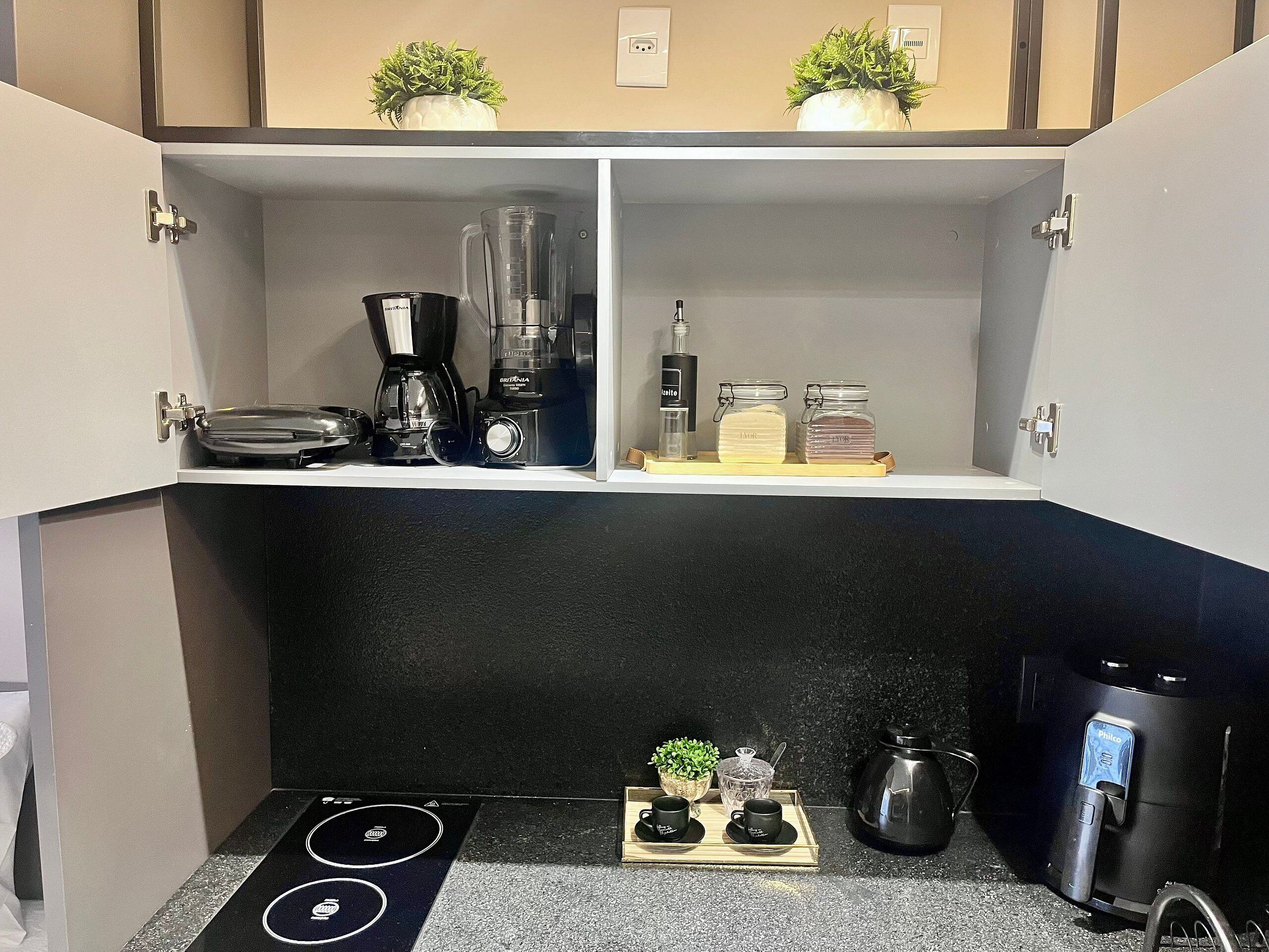 A kitchen with a black countertop, a coffee maker, a blender, and a kettle.