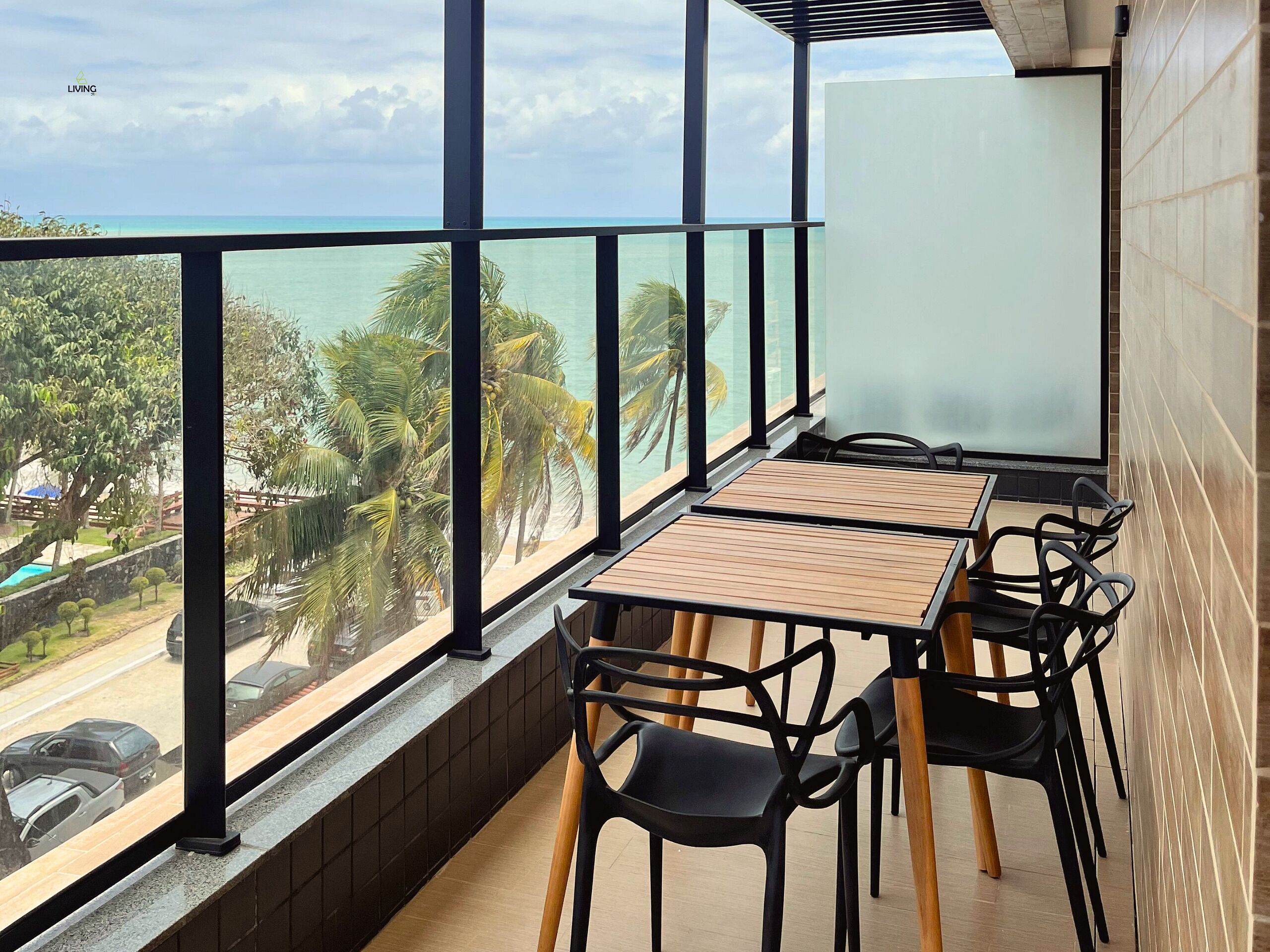 En balkon med udsigt over havet og palmer, med et bord og stole.