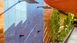 A tiled wall with a modern showerhead and a potted plant. - Hyde Park - By Living (João Pessoa)