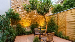 A patio with a stone wall, a wooden fence, and a table with chairs. - Kalamata Gem Retreats, Hidden In the City Center (Kalamata)