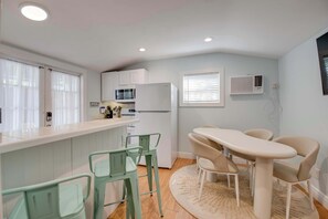 A compact kitchen with a refrigerator, microwave, and a dining area with chairs and a table. - Shared Pool & Parking - The Cottage at James House (Key West)