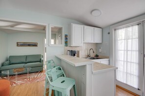 A compact living space with a kitchenette, a sofa, a dining area, and a view of the outdoors. - Shared Pool & Parking - The Cottage at James House (Key West)