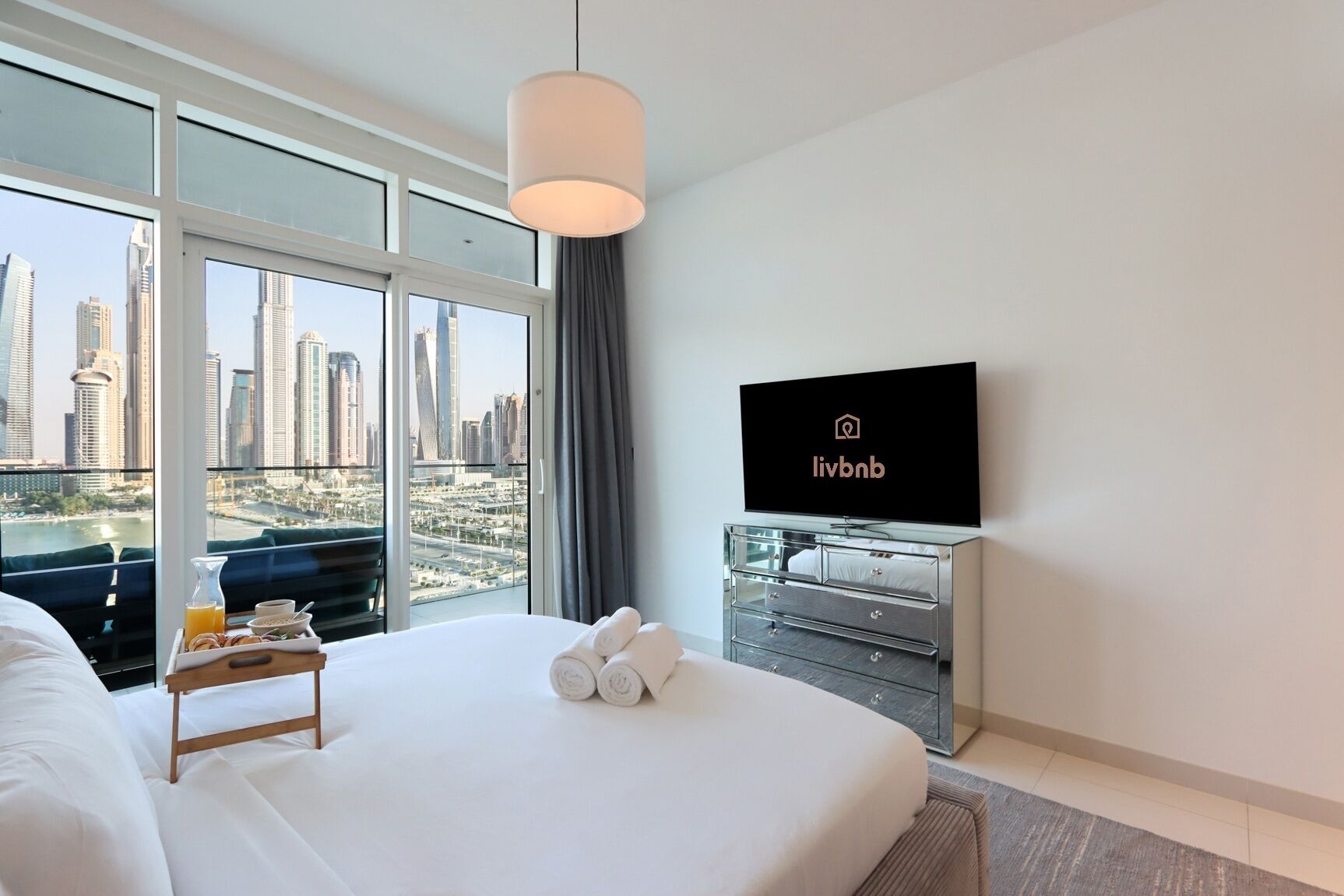 Une chambre d’hôtel avec un grand lit, un téléviseur fixé au mur et une vue sur la ville.