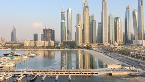 A marina with yachts and a city skyline with modern skyscrapers. - 2BR Beachfront Living, Stunning Marina Views (Dubai)
