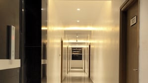A long, well-lit hallway with a marble floor, leading to a door marked with the number 101. - Hacana Millenium Hotel (Hyderabad)
