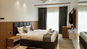 A modern hotel room with a large bed, a ceiling fan, a TV mounted on the wall, and a small bedside table. - Hacana Millenium Hotel (Hyderabad)